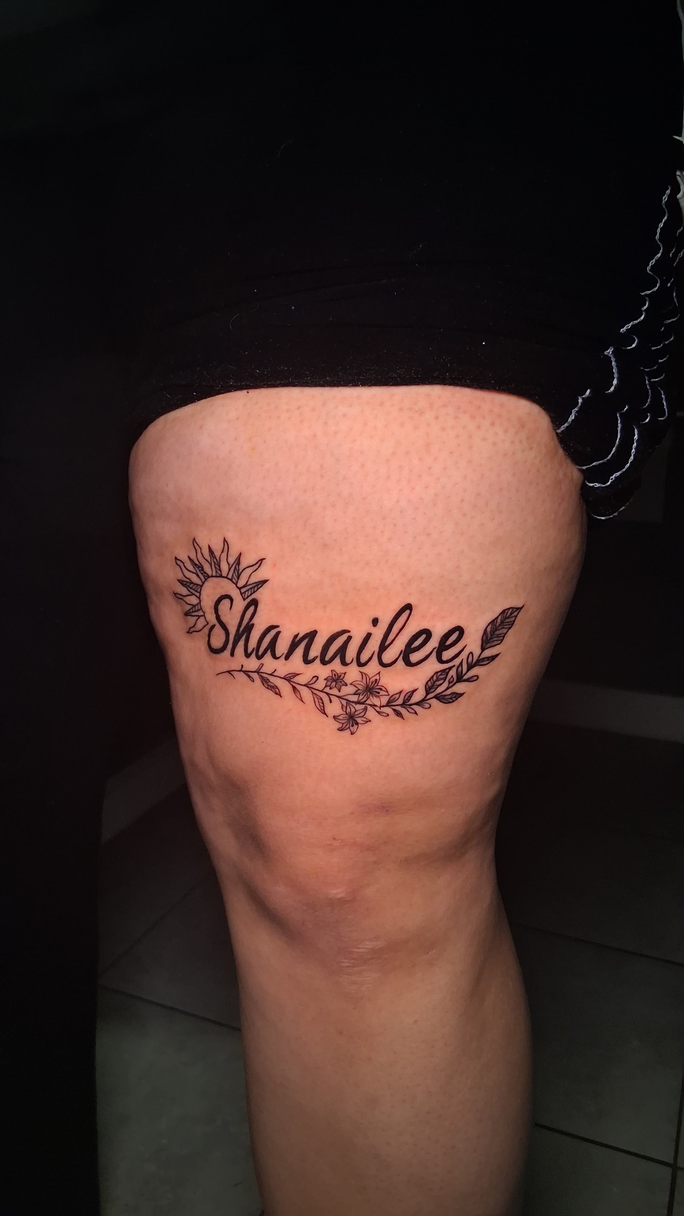 A solid black lettering I did on myself with a sun on the left and some leaves and flowers under it
