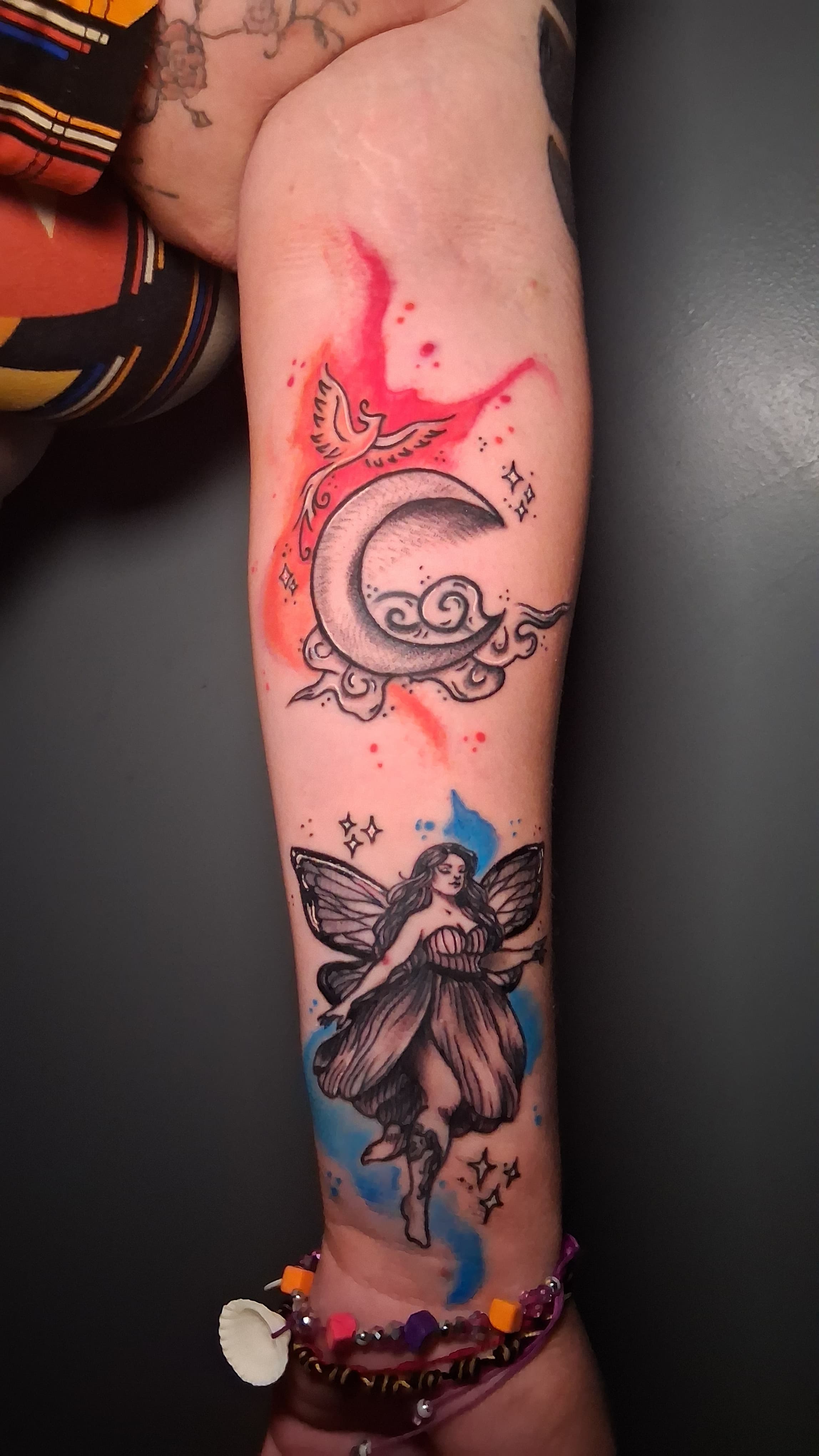 A phoenix bird with red and orange watercolor ink flow flying besides the moon and a fairy with a acuario tattoo on her leg and blue watercolor ink flow.